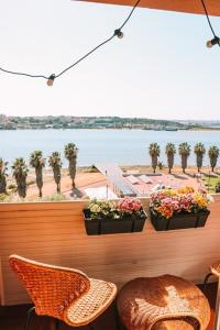 een balkon met 2 planten en stoelen en uitzicht op het water bij Golden Place - Seixal in Arrentela
