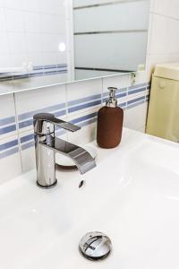 un lavabo avec un robinet et un distributeur de savon dans l'établissement Golden Place - Seixal, à Arrentela