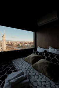 Schlafzimmer mit einem großen Fenster und einem Bett mit Kissen in der Unterkunft Eagle's Nest Short Stay in Baia Mare