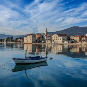 a small boat in the water in front of a town at DaMa in Kaštela