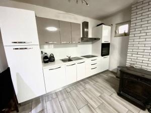 a white kitchen with white cabinets and a fireplace at DaMa in Kaštela