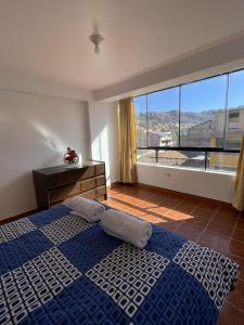 ein Schlafzimmer mit einem blauen Bett und einem großen Fenster in der Unterkunft Departamento Amoblado en el Centro de Cusco in Cusco