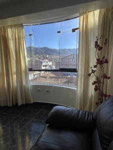 ein Wohnzimmer mit einem großen Fenster und einem Sofa in der Unterkunft Departamento Amoblado en el Centro de Cusco in Cusco