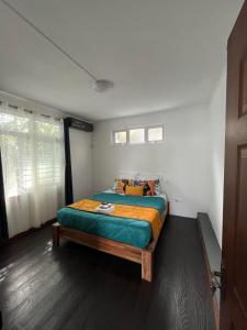 sypialnia z łóżkiem z zielonym i pomarańczowym kocem w obiekcie Le Manguier w mieście Mahébourg