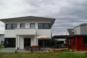 Casa blanca con banco y sombrilla en Apartment Suda, en Rheinhausen