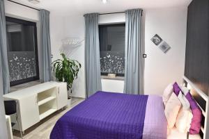 um quarto com uma cama roxa e uma janela em Water Lily Boutique B&B and Bungalow em Hévíz
