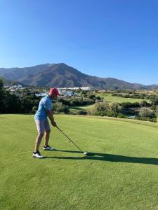 a woman is playing golf on a golf course at Bermeja view apartment in Manilva