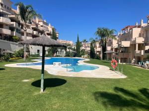 a swimming pool with an umbrella next to a building at Bermeja view apartment in Manilva