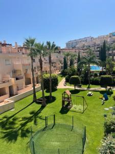 a playground in a park with palm trees and buildings at Bermeja view apartment in Manilva