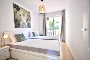 a white bedroom with a bed and a window at Bermeja view apartment in Manilva
