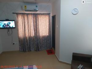 ein Wohnzimmer mit einem Vorhang und einem TV in der Unterkunft Affordable lovely apartment 3 in Accra