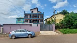 a blue car parked in front of a house at Affordable lovely apartment 3 in Accra