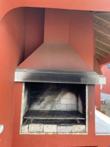an outdoor pizza oven with a red wall at A Casa do Comandante in Lagoa