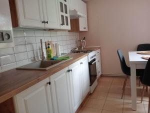 a kitchen with white cabinets and a sink at Domek Pod Sosnami D in Krasnobród +8 photos