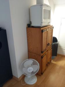 a room with a fan and a tv on a dresser at Chambre privée +thé et café 