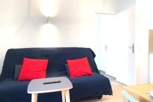 Sofá azul con 2 almohadas rojas y mesa en Appart'Village Le Creusot N4 NeufNetflix, en Le Creusot