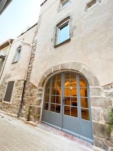 a stone building with a gray door on a street at La Source in Saint-Saturnin-de-Lucian
