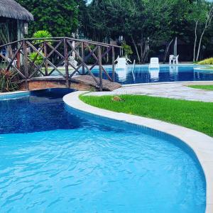 a swimming pool with a wooden bridge and blue water at ILOA Residence Flat Alagoas in Barra de São Miguel