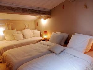 2 camas en una habitación con almohadas blancas en La maison perchée, en Aigues-Mortes