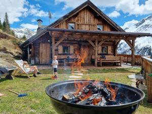 a boy standing in front of a fire in front of a log cabin at Almhütte Chrisanten Thaya Sölden in Sölden