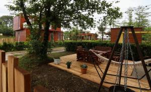 eine Holzterrasse mit einer Schaukel und einem Baum in der Unterkunft Cottages in Kaprovani "Family nest" in Ureki