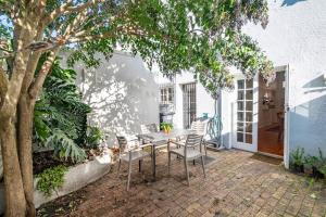 a patio with a table and chairs and a tree at Enchanting Abode in Rosebank in Cape Town