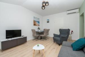 a living room with a couch and a tv and a table at Apartman Marin in Makarska