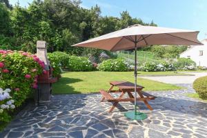 una mesa de picnic y una sombrilla en el patio en Apartamentos Rurales El Cuetu, en Picones
