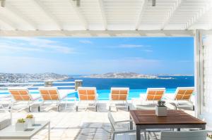 um pátio com cadeiras e mesas e vista para o oceano em Aeri Villas & Apartments em Tourlos