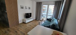 sala de estar con sofá azul y TV en Apartament 6 en Gołdap