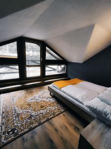 a bed in a room with windows and a rug at Chatka Gatterhof in Hodruša