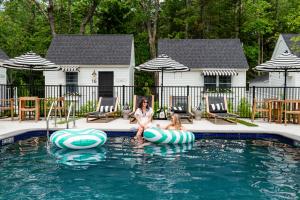 uma mulher e uma rapariga sentados em insufláveis numa piscina em Wanderer Cottages em Kennebunk