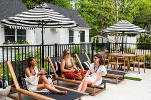 tres mujeres sentadas en sillas de césped bajo sombrillas en Wanderer Cottages, en Kennebunk