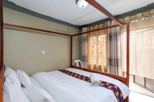 een slaapkamer met een bed met witte lakens en een raam bij Haber Motel Enterprise Ltd in Entebbe