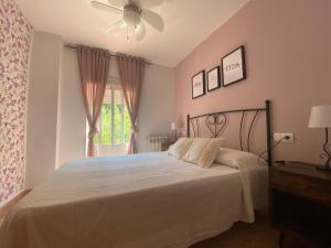 Un dormitorio con una cama con ventilador de techo y una ventana. en Apartamento Rosa, en Arroyo Frío