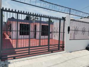 an iron gate with a pink house behind it at Casa Santa Cruz in Chetumal