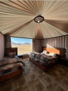een slaapkamer met twee bedden en een groot raam bij Enjoy Wadi Rum stars in Disah