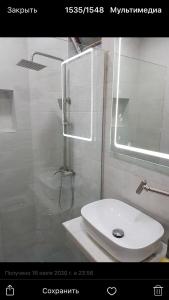 La salle de bains est pourvue d'une douche et d'un lavabo blanc. dans l'établissement My House, à Bordjomi