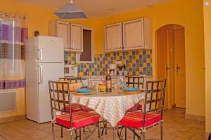 a kitchen with a table with chairs and a white refrigerator at Le Mas des Sagnes in Collias