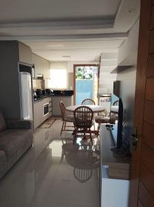 a kitchen and living room with a table and chairs at Refúgio Aconchegante em Canela in Canela