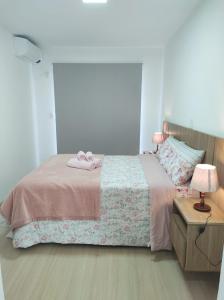 a bedroom with a bed with two pink slippers on it at Refúgio Aconchegante em Canela in Canela