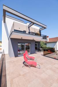 a pair of red chairs on the patio of a house at Residence Bella Vista in Bibinje