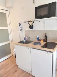 a small kitchen with a sink and a microwave at Studio COSY avec terrasse St Barthélémy in Saint-Barthélemy-dʼAnjou