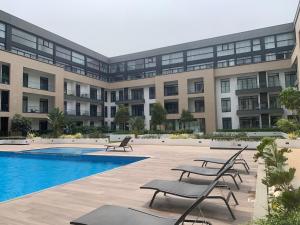 a large building with a pool and chairs in front of it at Ghana luxury Apartments in Accra