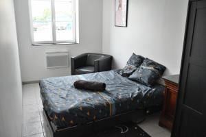 ein kleines Schlafzimmer mit einem Bett und einem Stuhl in der Unterkunft La Domus Lemaitre - Parking - Wifi TV - autoroute in Lieu-Saint-Amand