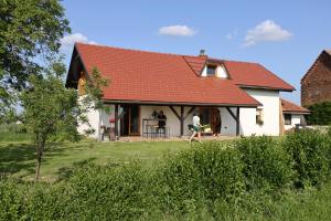 una casa con techo rojo y una persona sentada en el porche en Hiška pod Klumpo, en Ormoz