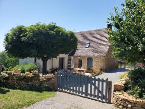 a house with a wooden fence and a tree at Le Pech de Vigne in Bio