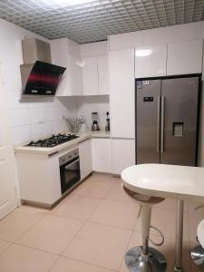 a white kitchen with a stainless steel refrigerator and a table at Country Block-Holiday home in Kgaphamadi