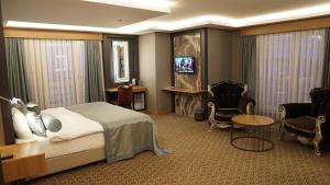 a hotel room with a bed and a tv and chairs at Green Prusa Hotel in Bursa