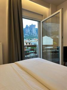 a bedroom with a bed and a large window at Meteora Gold and Glass in Kalabaka